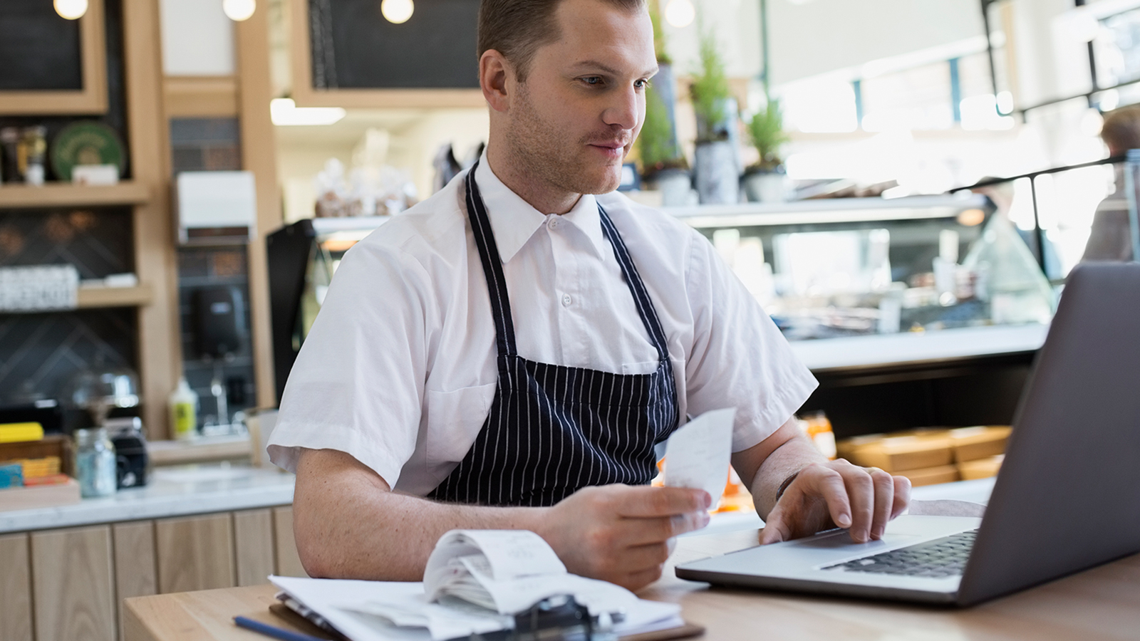 A man inside a café, working at his laptop.